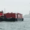 The tugboat Pegasus and the Lehigh Barge no. 79 passing the Statue of Liberty in the rain.